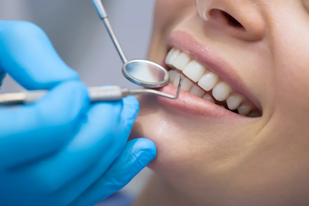 Dentist's mirror and gloved hand examining a patient's teeth